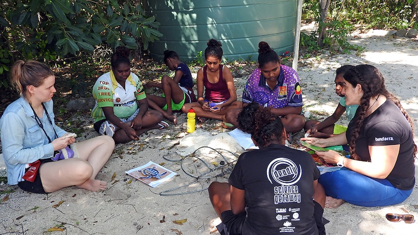 Indigenous girls sitting in a circle and discussing education and career options with university staff.