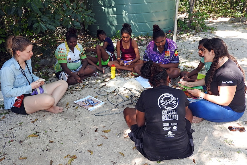 Indigenous girls sitting in a circle and discussing education and career options with university staff.