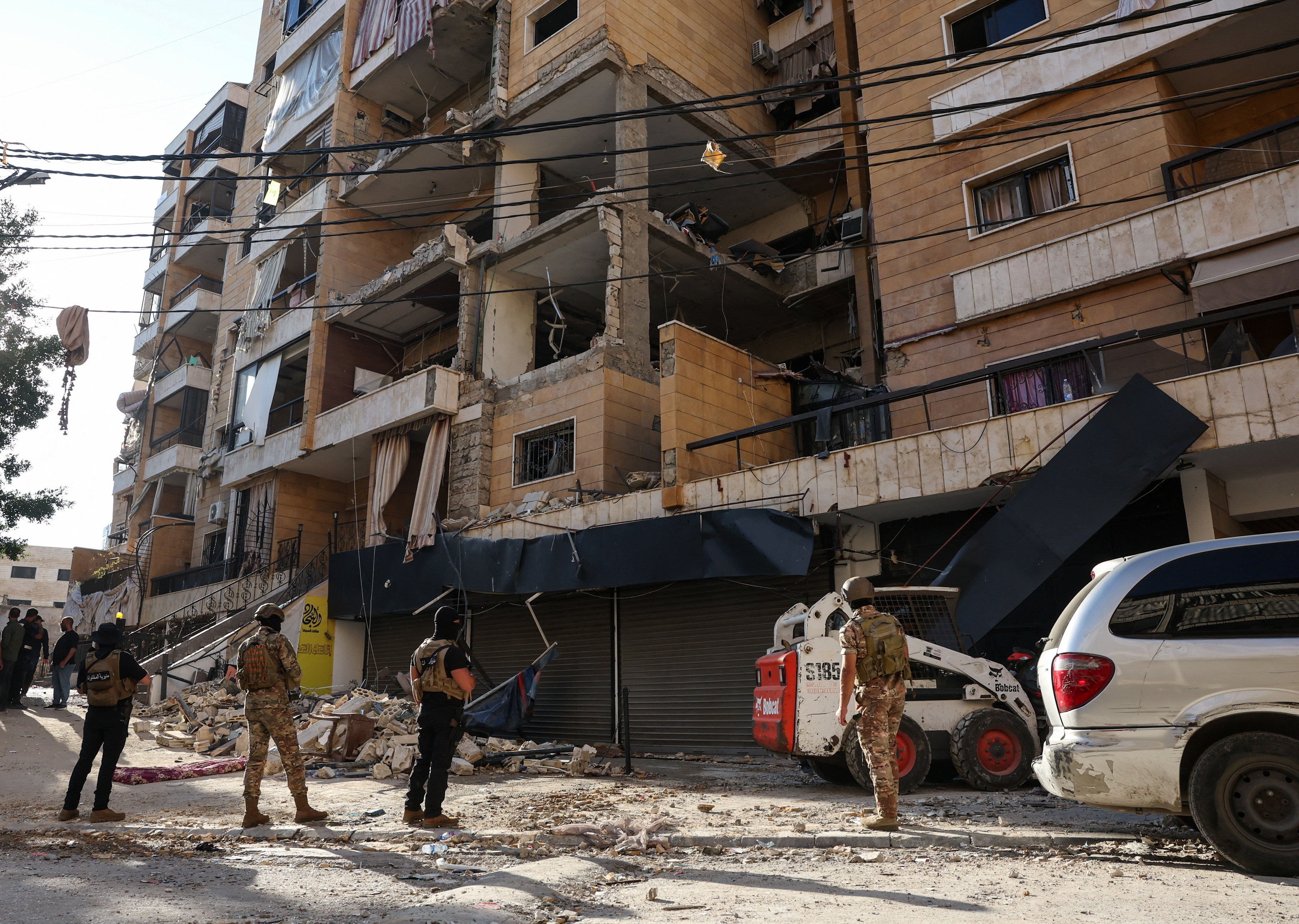 A group of men in military uniforms standing near a damaged building