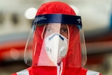 A close-up shot of a male doctor decked out in a PPE face shield and orange hood.