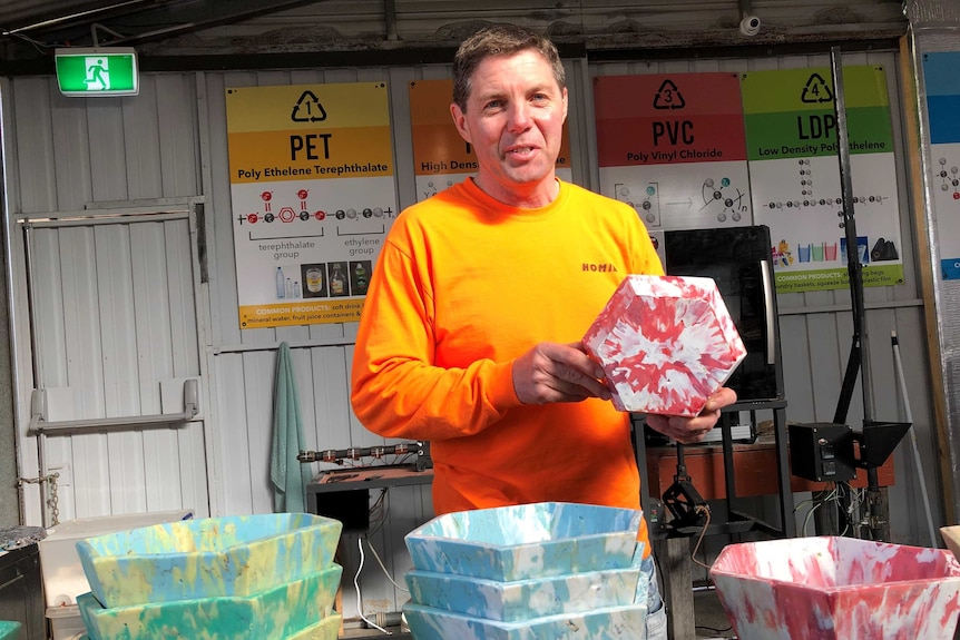 Recycler Brad Scott poses with the bright pink bowl he has made from 1,870 used bread tags.