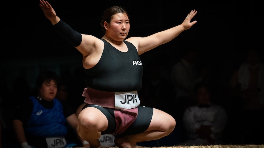 A woman crouching down with her arms outstretched 