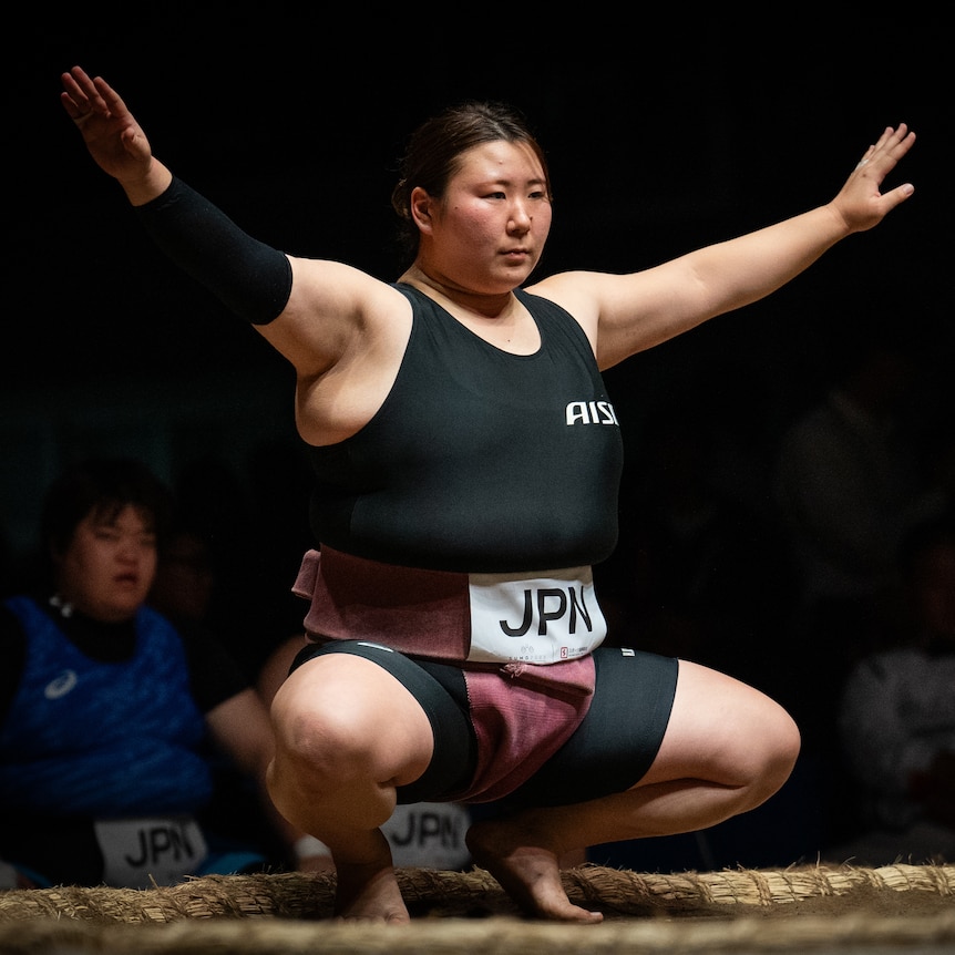 A woman crouching down with her arms outstretched 