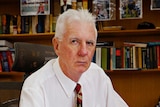 Northern Territory coroner, Greg Cavanagh, looks into the camera with a stern expression. He's in his office.
