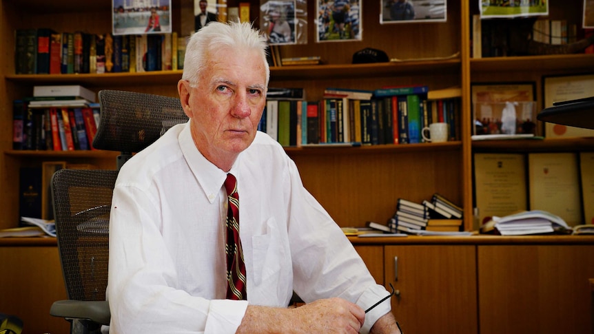 Northern Territory coroner, Greg Cavanagh, looks into the camera with a stern expression. He's in his office.