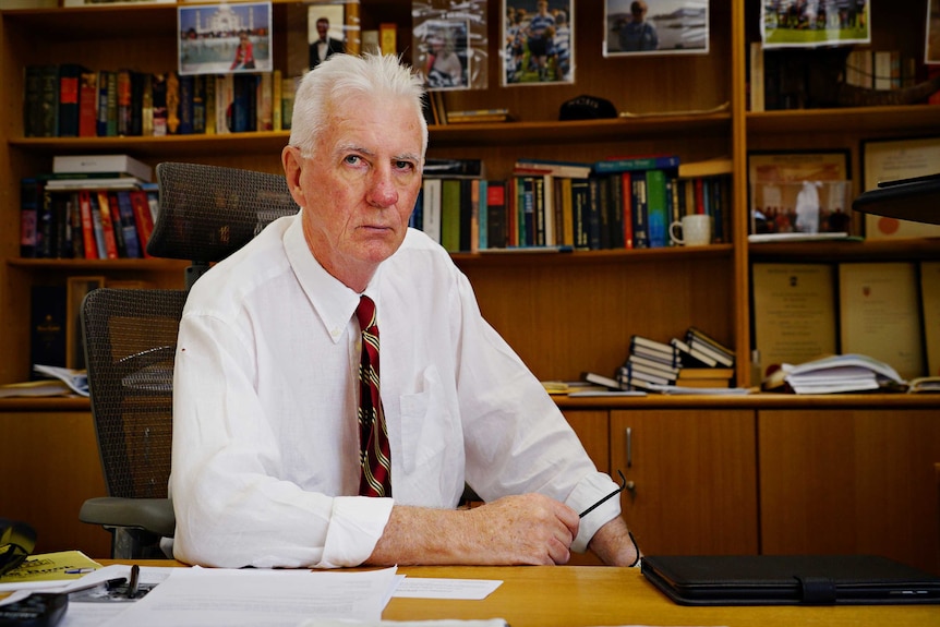 Northern Territory coroner, Greg Cavanagh, looks into the camera with a stern expression. He's in his office.