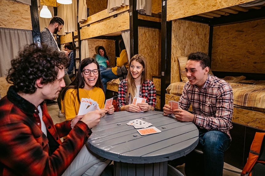 Young people playing cards in hostel.