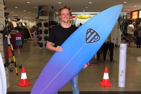 Surfer Tim Dickson posing for a photograph with his surfboard