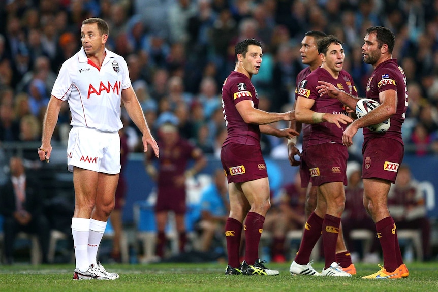 Maroons players look at referee Ben Cummins