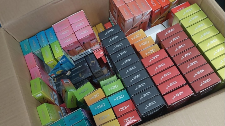 A large cardboard box containing colourful boxes of cigarettes.