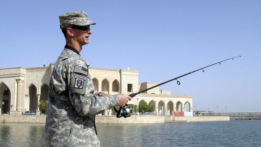 A US Army officer fishes in a lake surrounding the former palace of Saddam Hussein