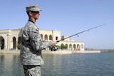 A US Army officer fishes in a lake surrounding the former palace of Saddam Hussein