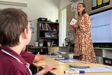 A young white woman teaching a primary school class