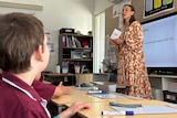 A young white woman teaching a primary school class