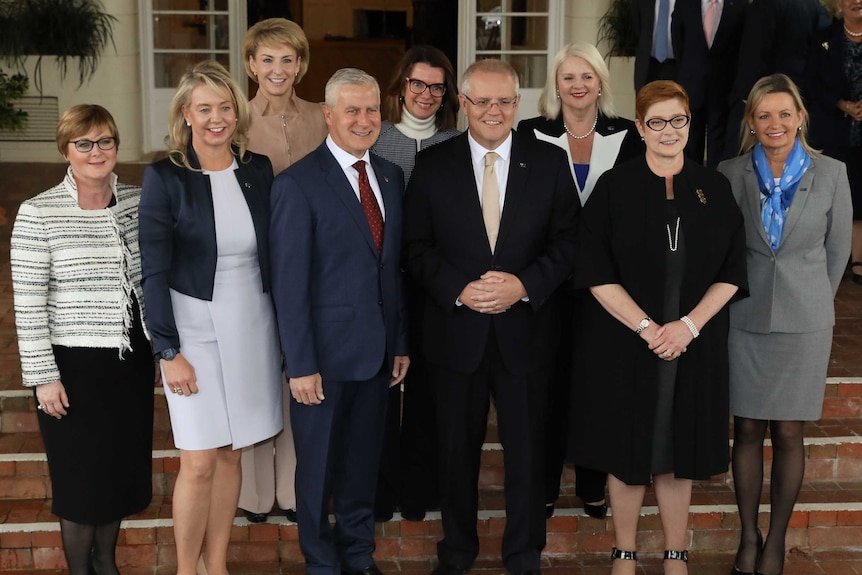 Mr Morrison and Mr McCormack are surrounded by the female members of Cabinet, as they stand on the steps of Government House.