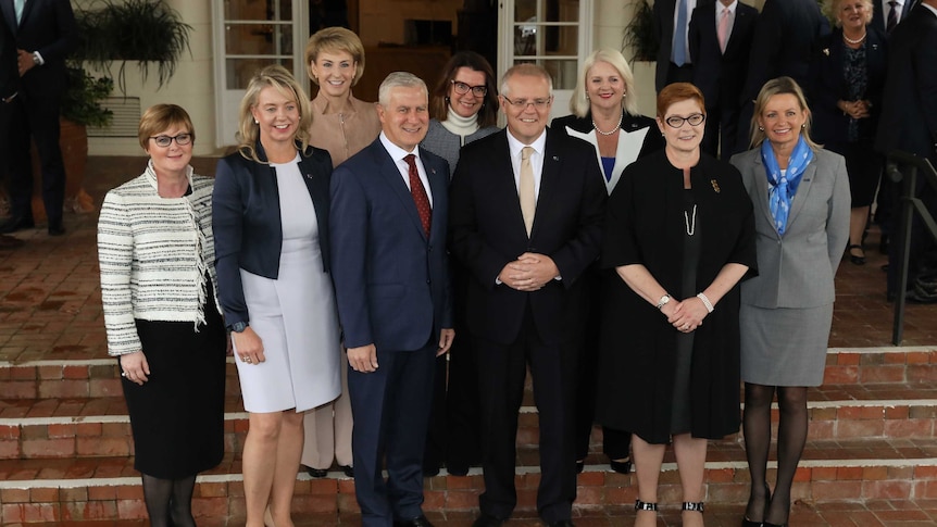 Mr Morrison and Mr McCormack are surrounded by the female members of Cabinet, as they stand on the steps of Government House.
