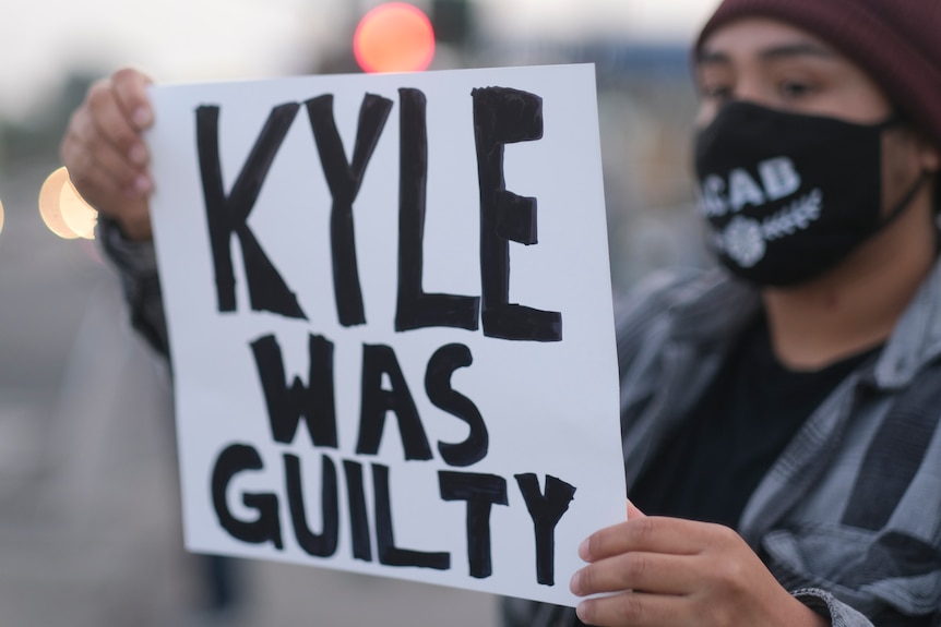 A protester holds a placard reading 'Kyle was guilty'