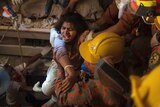 Bangladeshi rescue workers pull an injured garment worker from the rubble