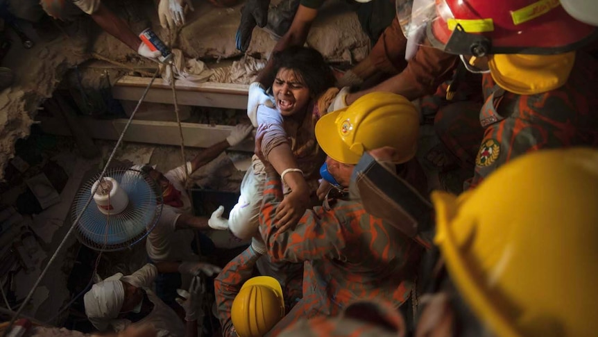 Bangladeshi rescue workers pull an injured garment worker from the rubble