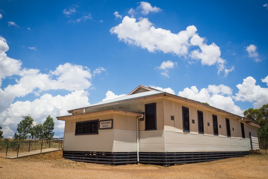 a wooden country hall with a concrete ramp under a blue sky