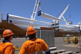 A large ship docked at a port with cargo being unloaded.