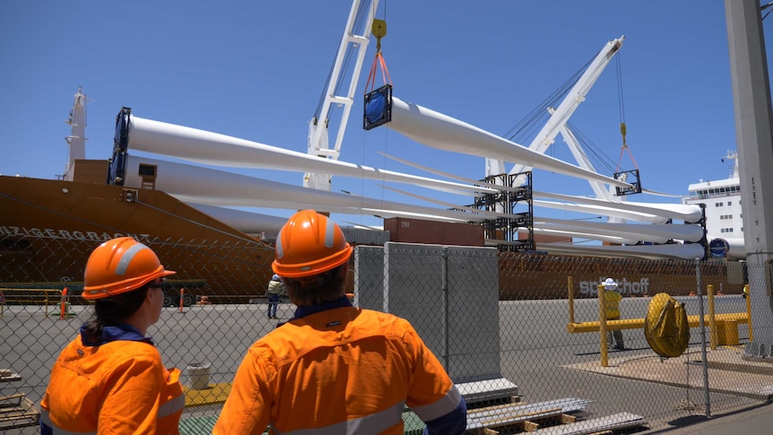 A large ship docked at a port with cargo being unloaded.