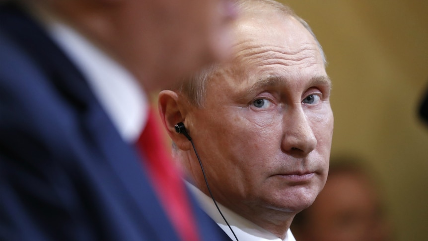 Russian President Vladimir Putin looks at Trump.