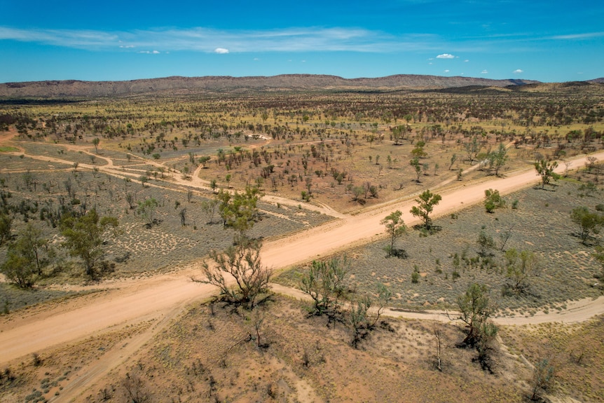 An aerial photo of a dirt road through a vast desert landscape