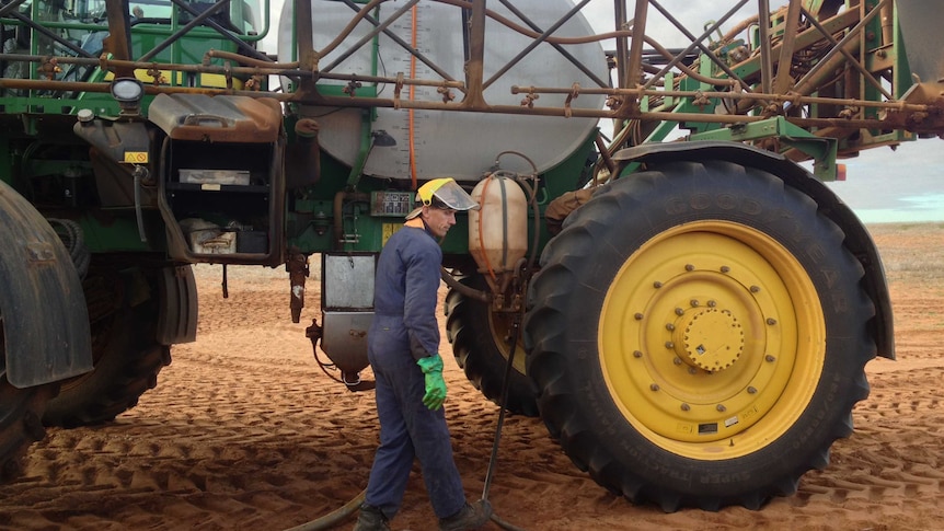 Robin Schafer stands in front of his John Deere tractor while filling up his spray unit.