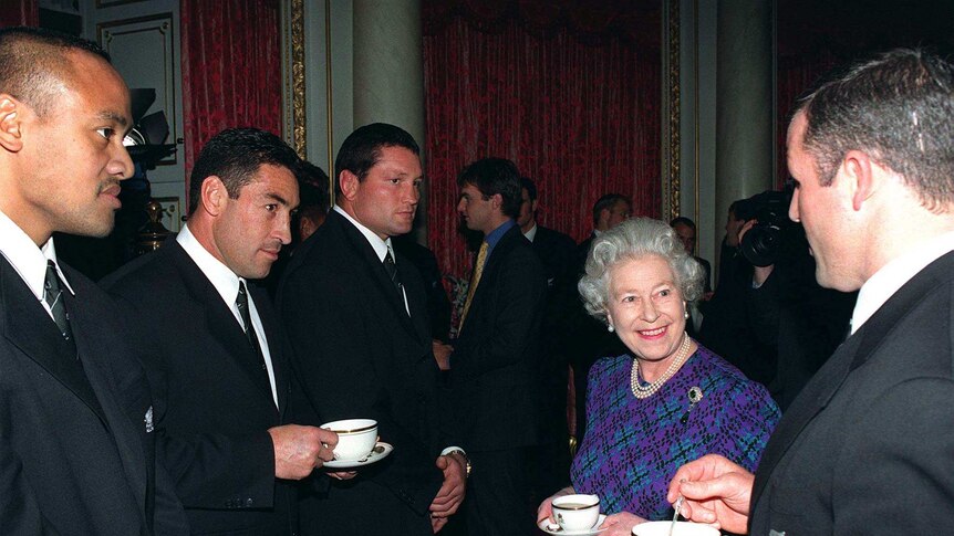 Queen Elizabeth drinking tea with All Blacks