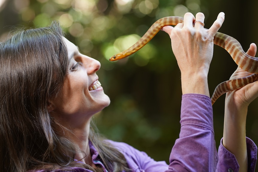 Profile of a woman holding up a snake