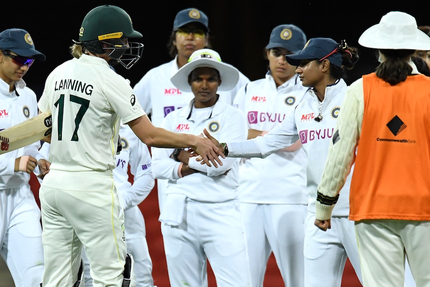 Meg Lanning, still in batting gear, shakes hands with Mithali Raj as the Indian team looks on