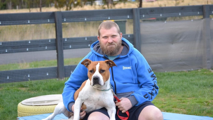 Dan Blackwell sits with his dog Angel on his lap.