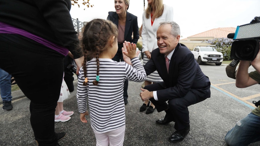 Bill Shorten high fives a child on the campaign trail in Perth.