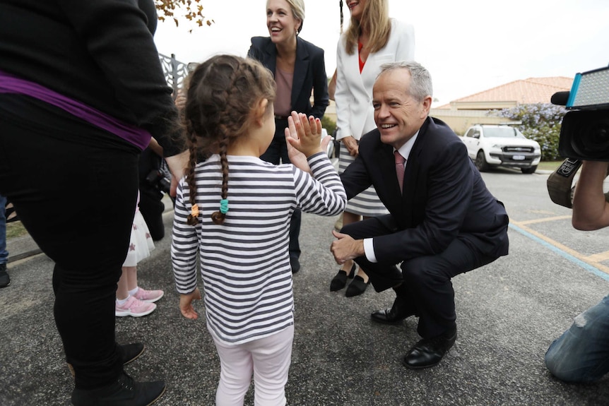 Bill Shorten high fives a child on the campaign trail in Perth.