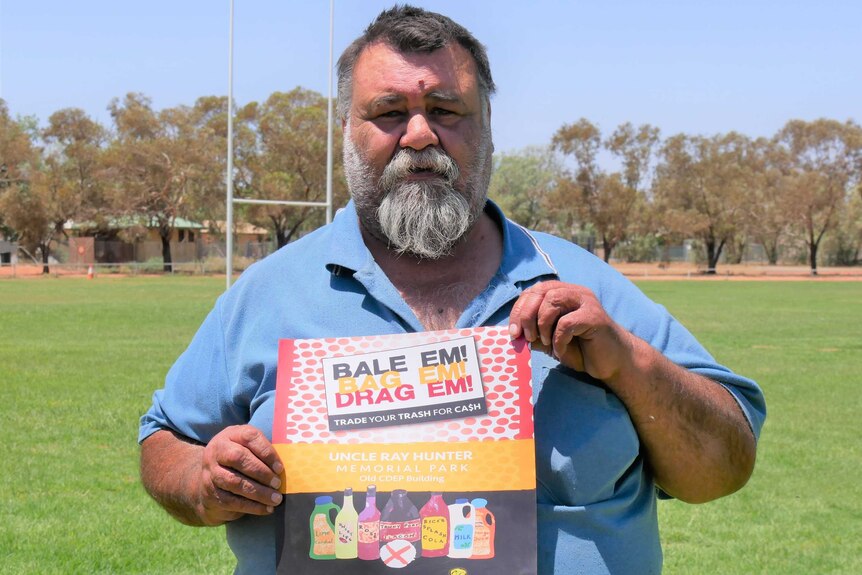 Kevin Cattermole holds a poster he designed about Wilcannia's "Return and Earn" scheme