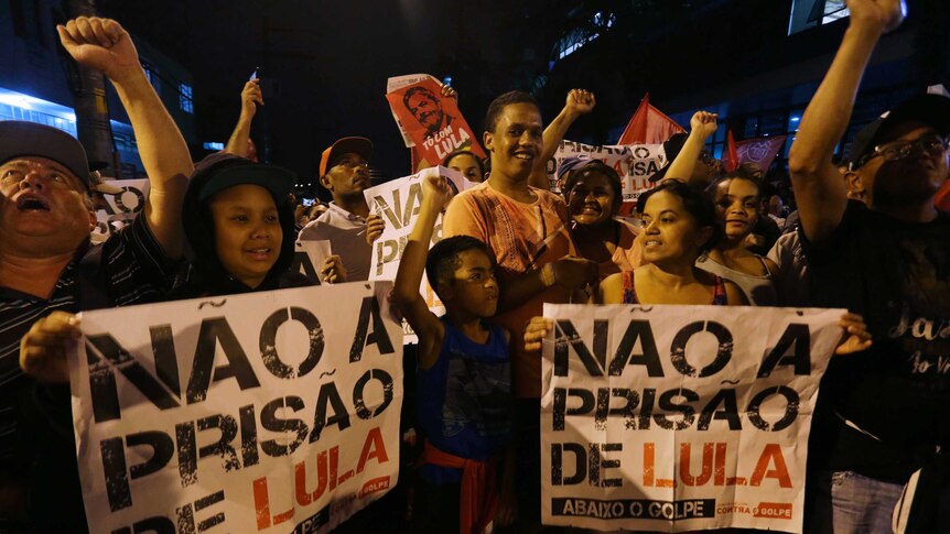 People holding signs that read in Portuguese "No to prison for Lula", waving hands.