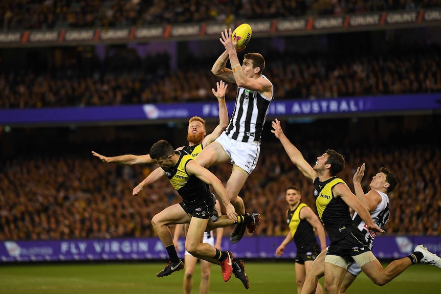 An AFL player flies for a mark in a pack at the MCG.