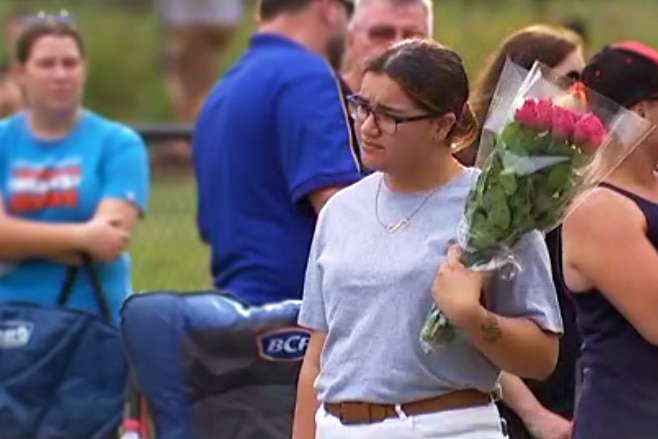 A woman in a park holds a bouquet of flowers.