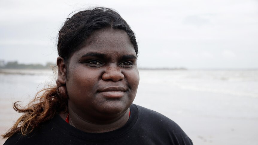 a young aboriginal woman at the beach wearing a black t shirt