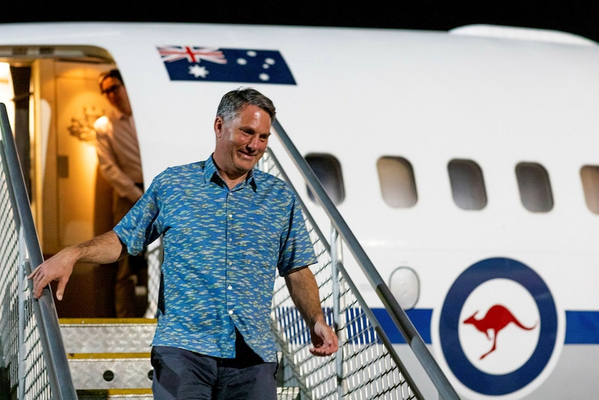 Marles in a tropical shirt steps off a plane.