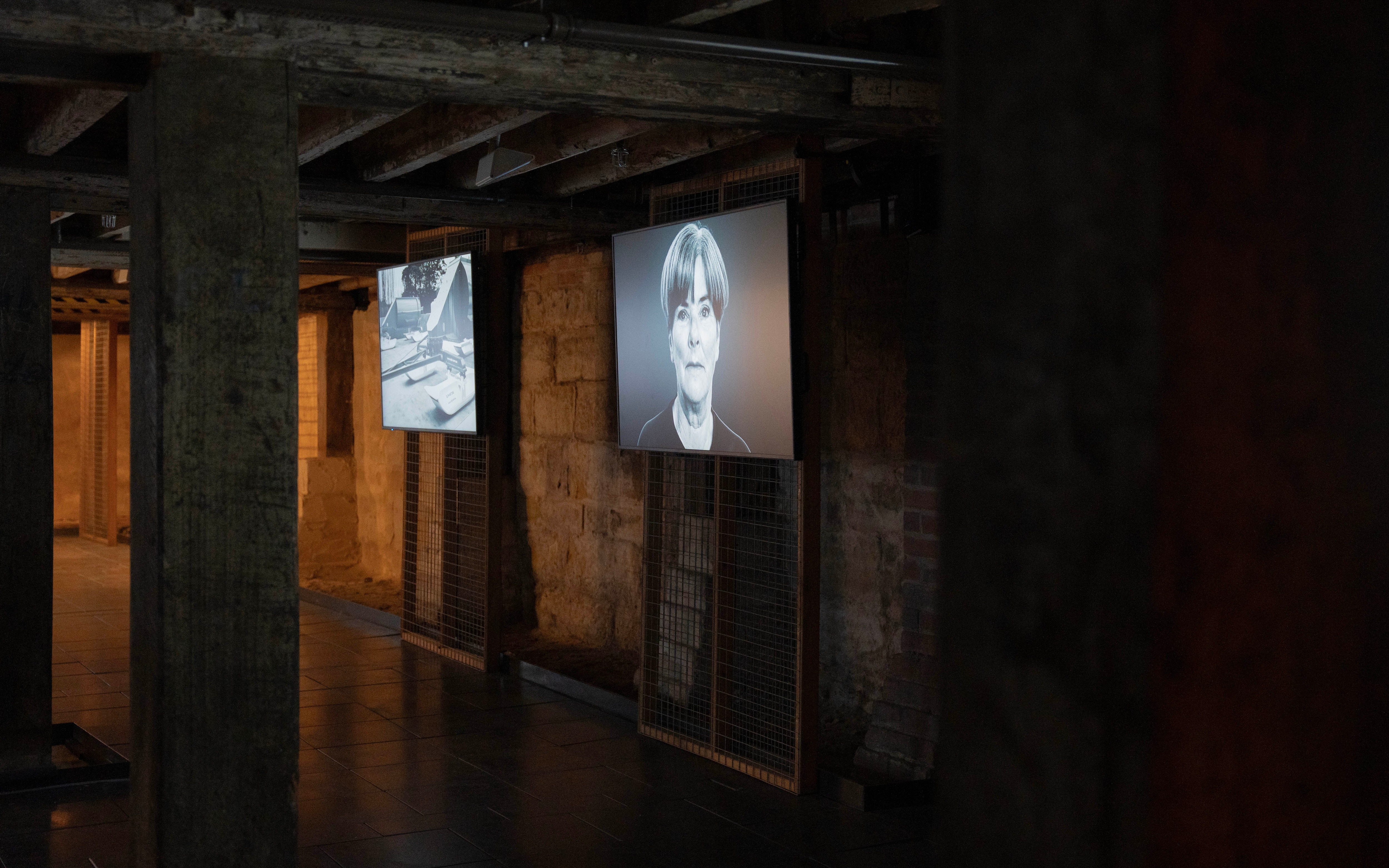 A dark room in a museum with black and white screens on the walls.