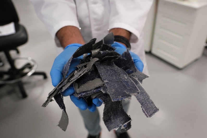 a person holds strips cut off a solar panel.