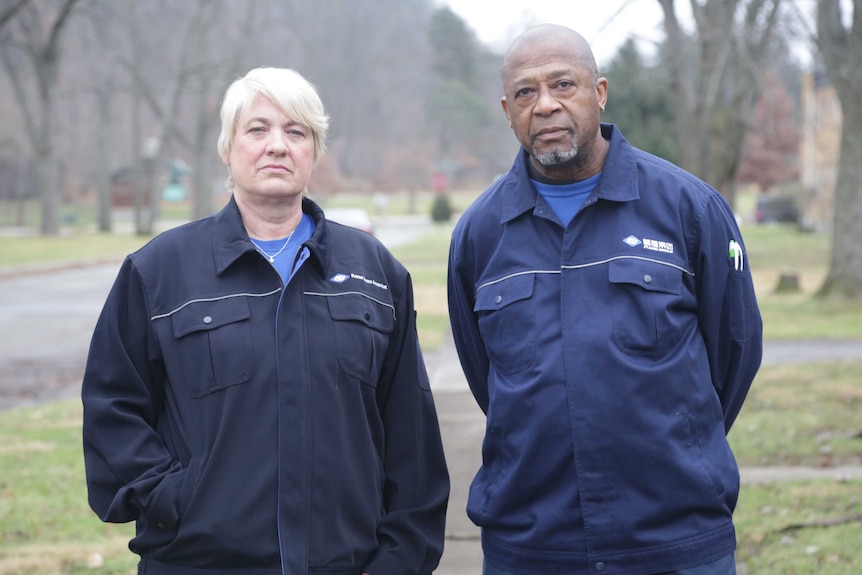 Two factory workers stare stony-faced