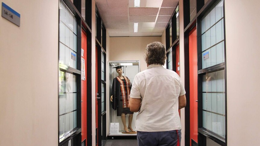 a woman walking down a corridor to a display of clothing