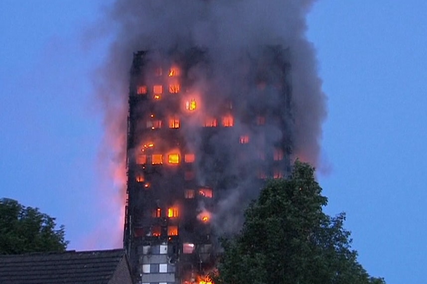 Fire burns at Grenfell Tower in London producing lots of smoke in the morning