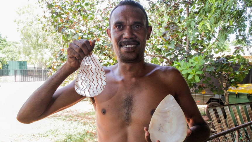 Terry Hunter with two carved pearl shells known as riji.