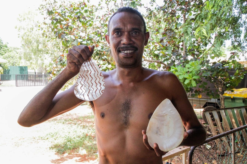 Terry Hunter with two carved pearl shells known as riji.