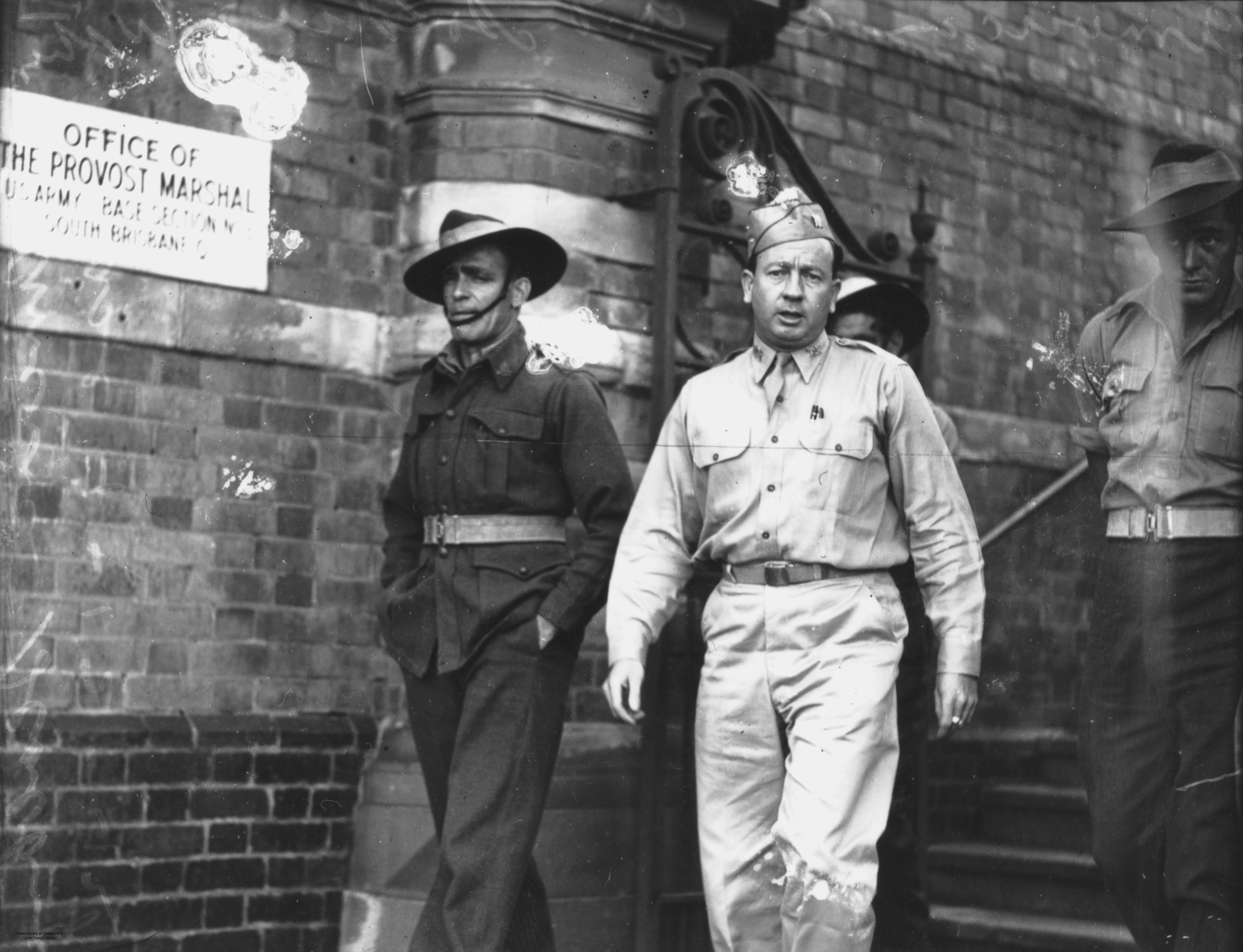 Black and white photo of two soldiers walking out of a building.