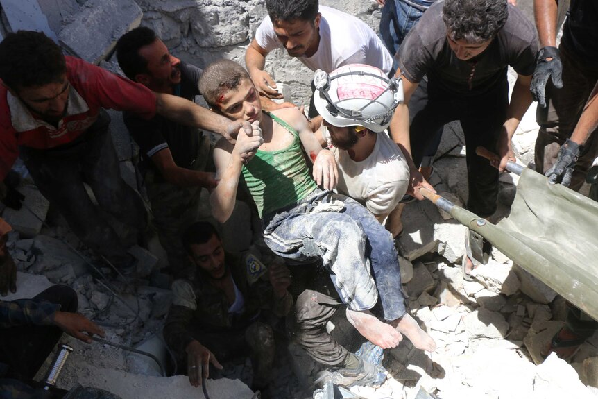 Syrian civil defence volunteers, known as the White Helmets, carry a young boy rescued in Aleppo.